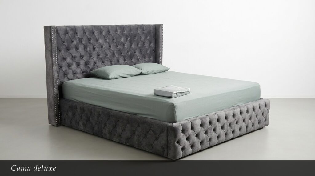 La Cama Deluxe es sinónimo de opulencia y máximo confort. Su enorme cabecera y base completamente capitoné en gris acero con tachuelas metálicas crean un efecto visual impactante y lujoso. El diseño integral tapizado ofrece una apariencia robusta y elegante al mismo tiempo.