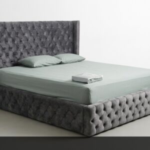 La Cama Deluxe es sinónimo de opulencia y máximo confort. Su enorme cabecera y base completamente capitoné en gris acero con tachuelas metálicas crean un efecto visual impactante y lujoso. El diseño integral tapizado ofrece una apariencia robusta y elegante al mismo tiempo.