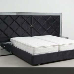 La Cama Executive combina lujo y modernidad con un toque audaz. Su espectacular cabecera en negro con diseño romboidal capitoné y marco de espejo brinda presencia y sofisticación. La base tapizada en negro y las mesitas de noche a juego completan un conjunto de alto impacto.