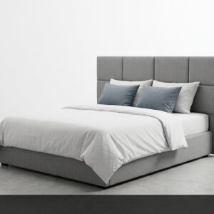 La Cama Style destaca por su diseño moderno y funcional. La cabecera tapizada en gris con paneles rectangulares ofrece un aspecto limpio y actual, mientras que la base baja aporta ligereza visual. Los cojines en azul grisáceo añaden un toque de color sutil y elegante.
