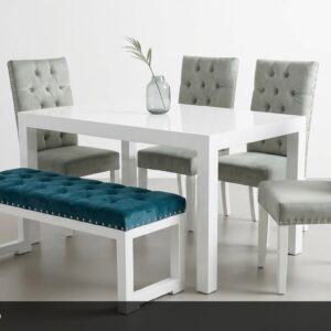 El Comedor Platino combina elegancia moderna con un toque de audacia. La mesa blanca de líneas rectas y superficie brillante se complementa con sillas tapizadas en gris platino con acabado capitoné y tachuelas decorativas. El banco en terciopelo azul turquesa añade un hermoso contraste de color y una nota de originalidad al conjunto.